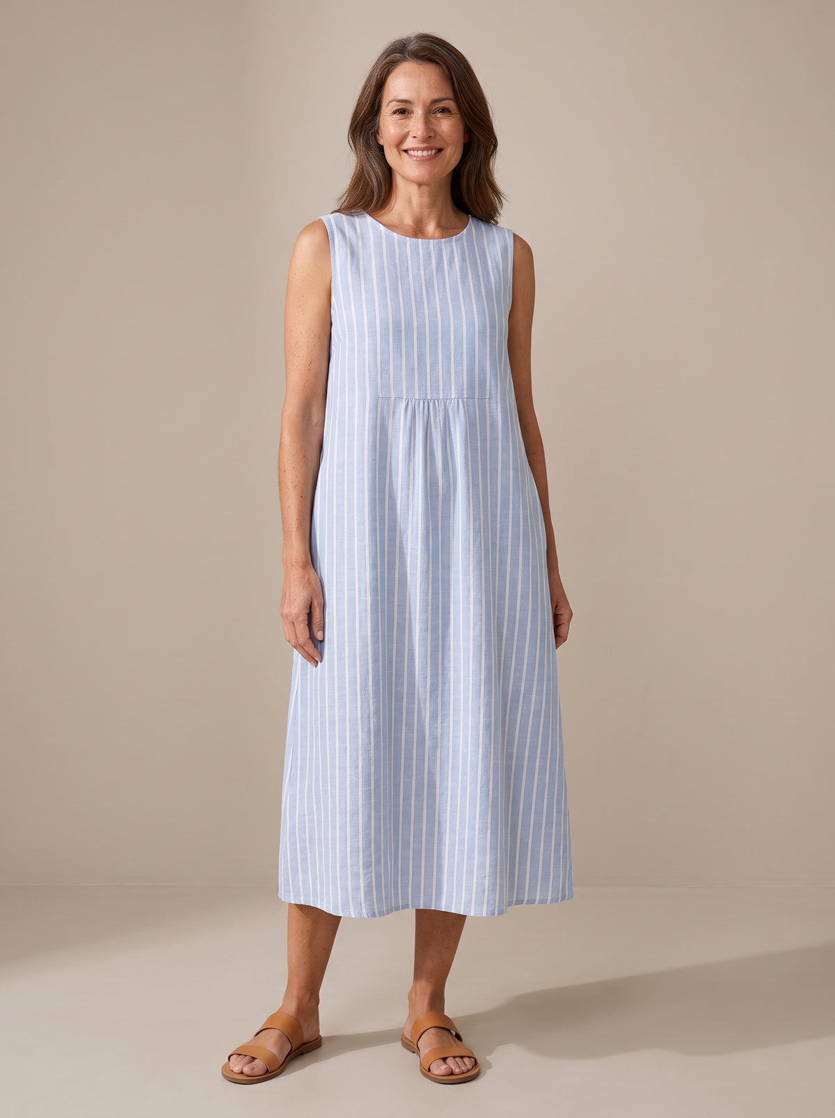 Woman wearing The Adele sleeveless midi dress in blue and white striped linen, front view