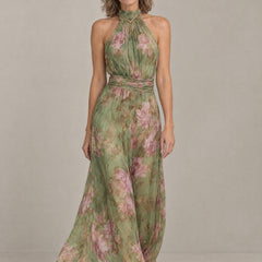 Woman wearing the Liora floral halter maxi dress in sage green chiffon with pink peonies, front view