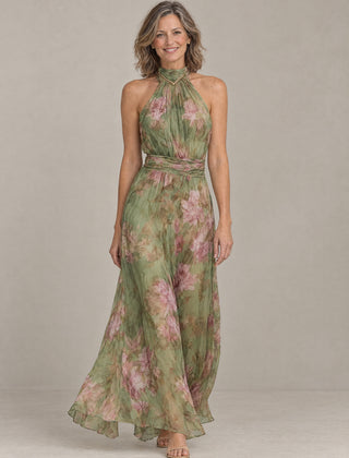 Woman wearing the Liora floral halter maxi dress in sage green chiffon with pink peonies, front view