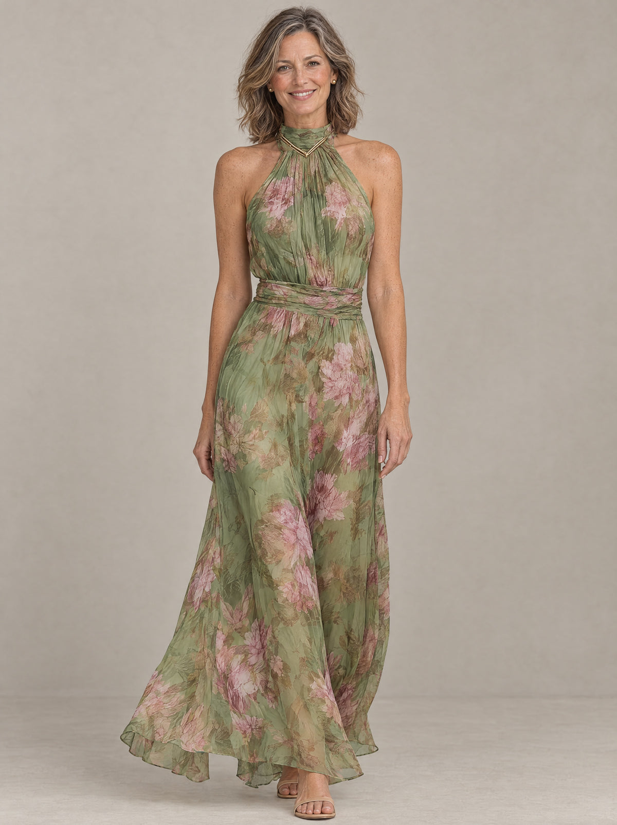 Woman wearing the Liora floral halter maxi dress in sage green chiffon with pink peonies, front view