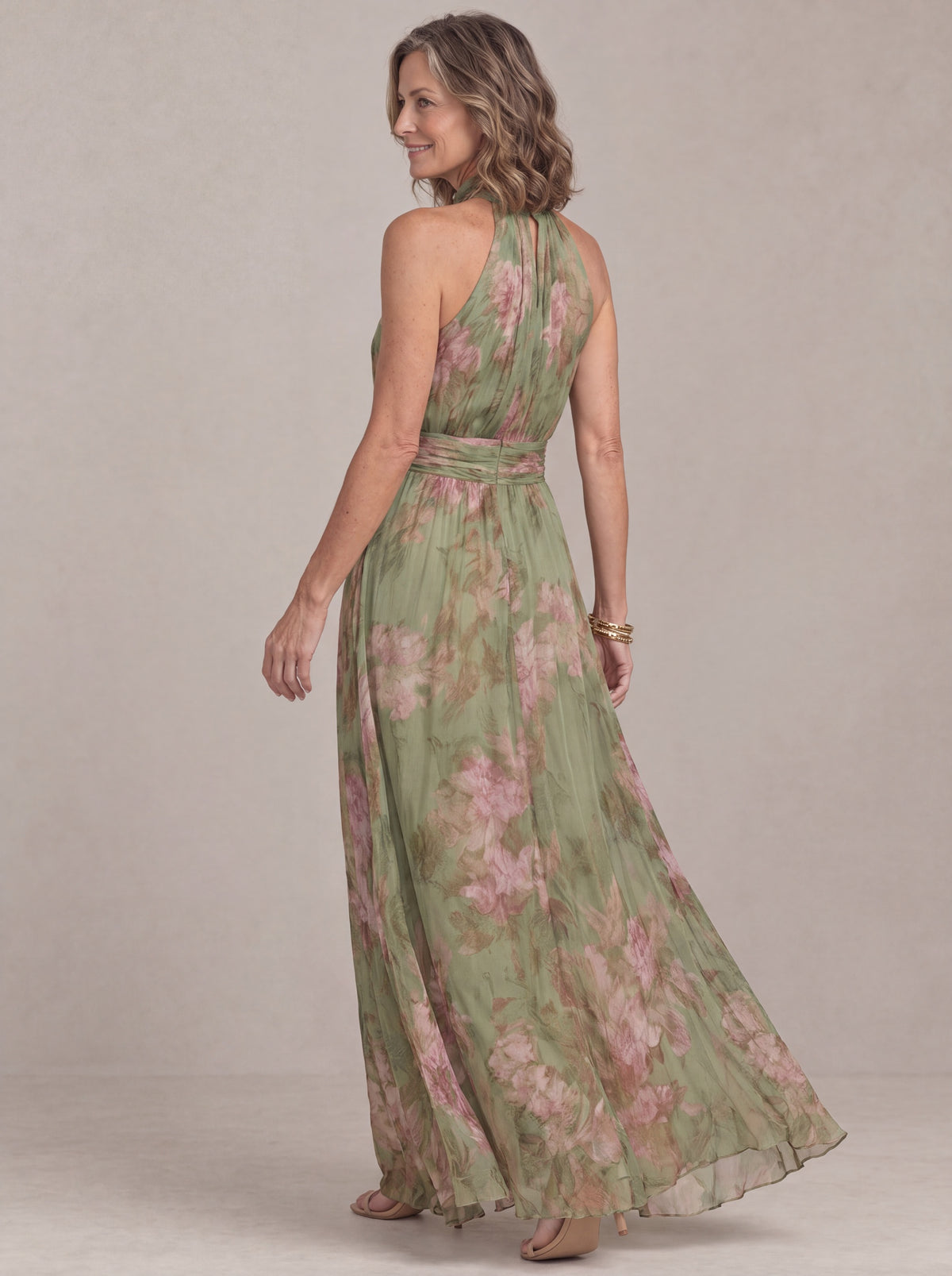 Liora halter maxi dress in sage green floral chiffon, back three-quarter view of the flowing skirt