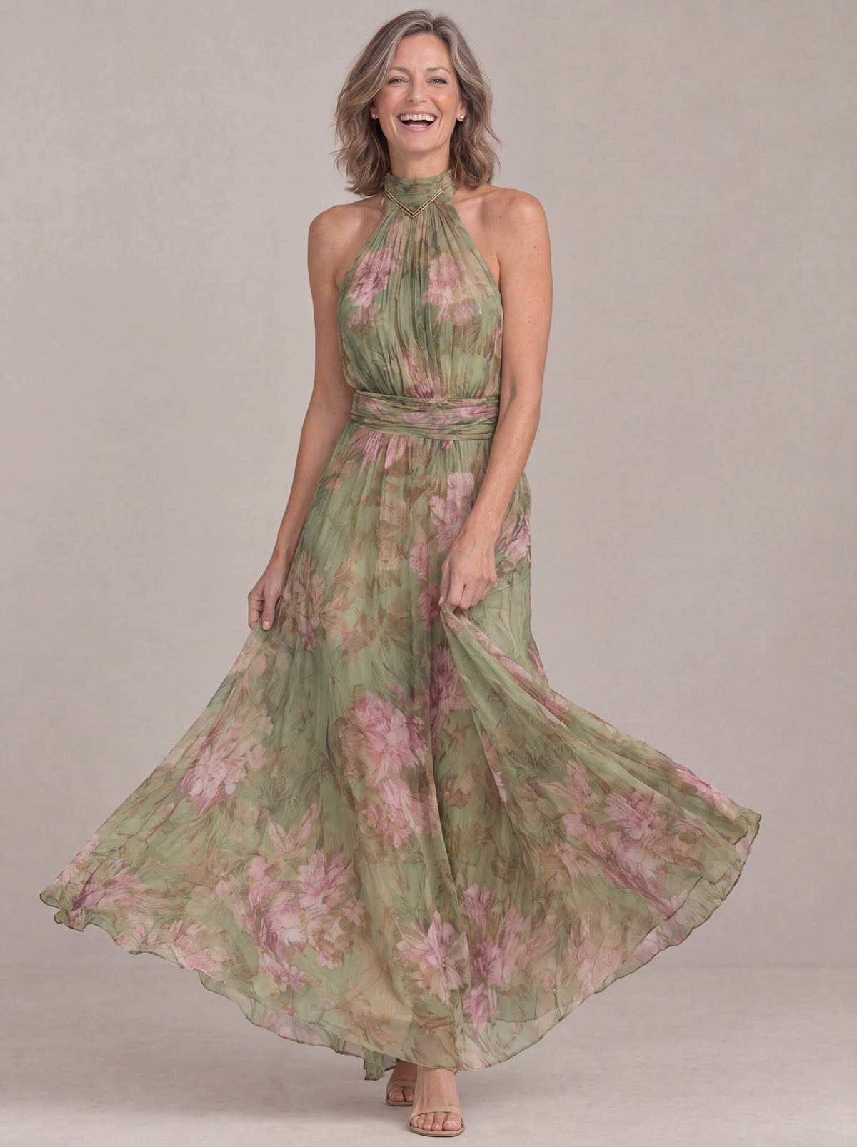 Smiling woman twirling in the Liora floral halter maxi dress, chiffon skirt swirling